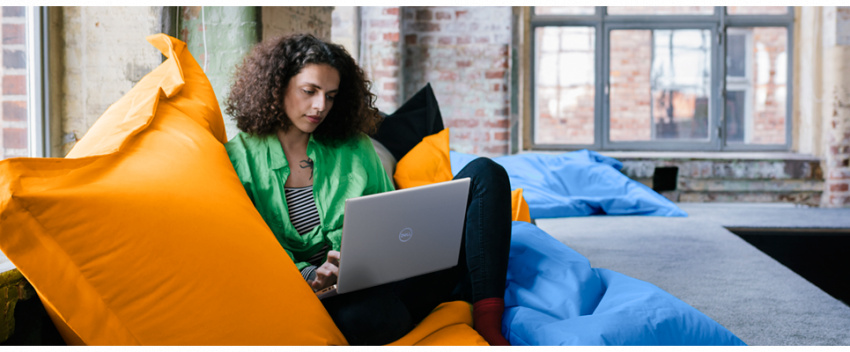 女子坐在黃色大型懶人沙發並將 Dell Inspiron 14 5420 筆記型電腦放在大腿上的圖片。